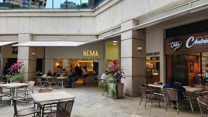 Área externa da Nema Padaria Barra Prime, com mesas na calçada